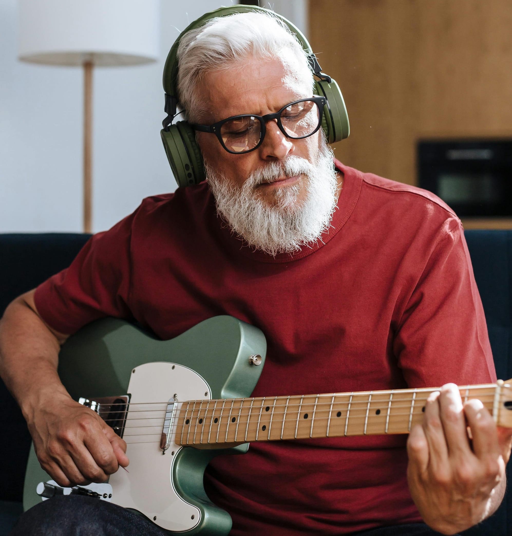 Older adult playing guitar with relaxed posture and gentle focus