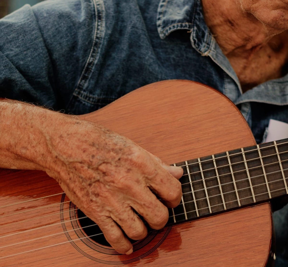 Middle-aged man playing guitar indoors, relaxed posture and focus