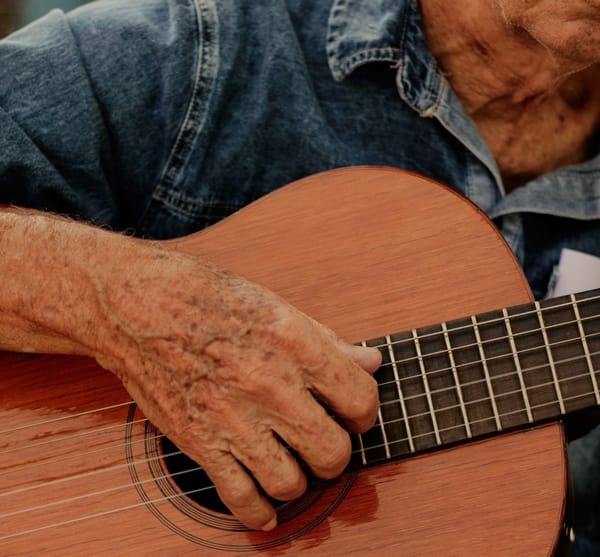 Middle-aged man playing guitar indoors, relaxed posture and focus
